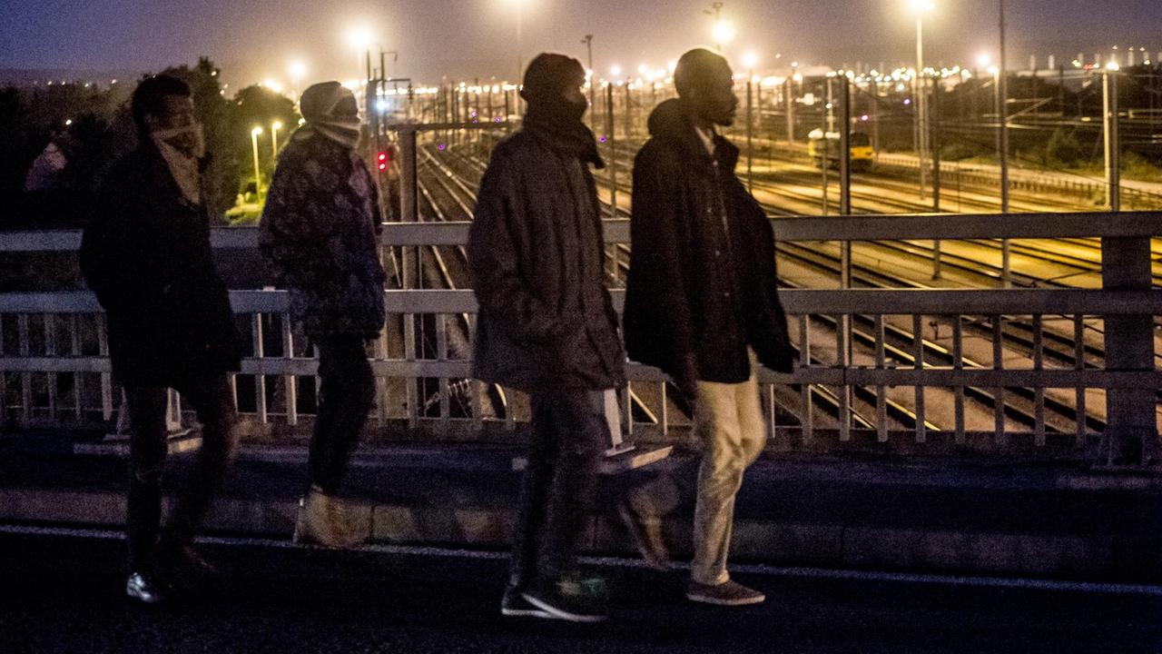 Migranten beim Überqueren einer Eisenbahnbrücke des Eurotunnel-Terminals in Frankreich am 28. Juli 2015. AFP PHOTO / PHILIPPE HUGUEN.