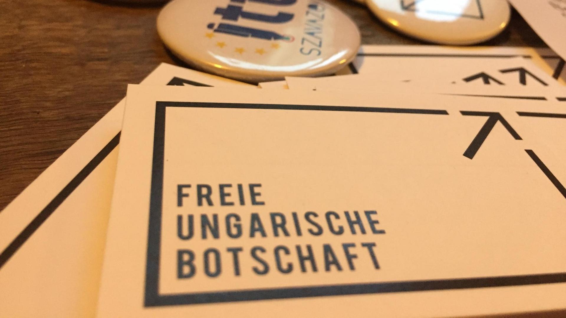 Flyer und Buttons mit der Aufschrift "Freie Ungarische Botschaft" liegen auf einem Tisch Flyer und Buttons mit der Aufschrift "Freie Ungarische Botschaft" liegen auf einem Tisch