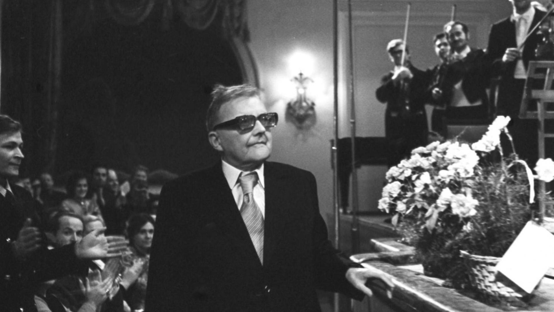 Dmitri Schostakowitsch im Moskauer Konservatorium bei der Uraufführung seiner letzten Sinfonie durch seinen Sohn. Rechts stehen Geiger bereit, links applaudiert das Publikum dem Komponisten. Dmitri Schostakowitsch im Moskauer Konservatorium bei der Uraufführung seiner letzten Sinfonie durch seinen Sohn. Rechts stehen Geiger bereit, links applaudiert das Publikum dem Komponisten.