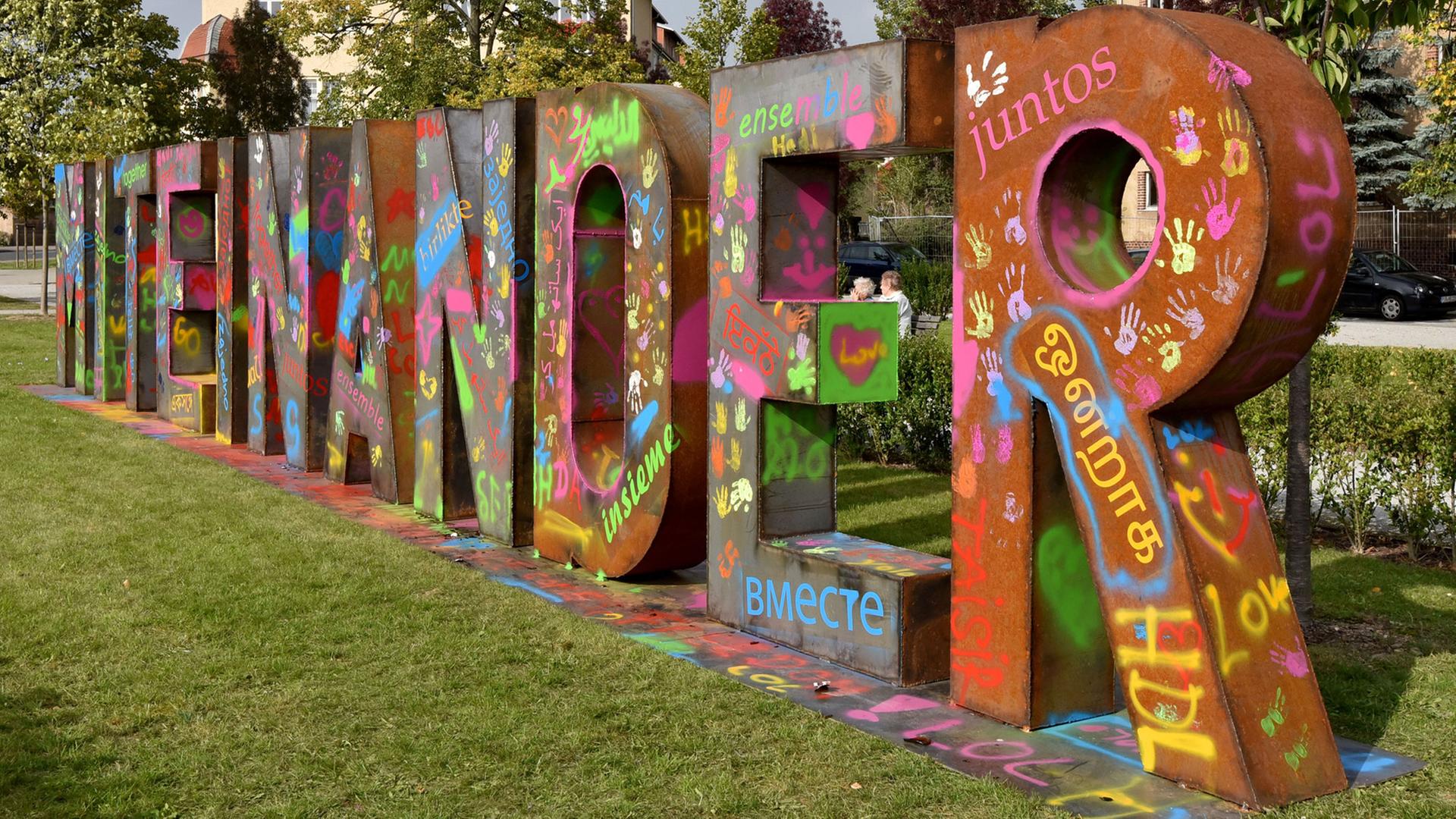 Die 15 Meter lange Metallskulptur «Miteinander» von Hüseyin Arda steht am 06.10.2015 in Heidenau (Sachsen). Gemeinsam besprüht mit Heidenauern, regionalen Künstlern und Kindern soll die Wortskulptur ein Zeichen für tolerantes und respektvolles umgehen miteinander setzen. Die 15 Meter lange Metallskulptur «Miteinander» von Hüseyin Arda steht am 06.10.2015 in Heidenau (Sachsen). Gemeinsam besprüht mit Heidenauern, regionalen Künstlern und Kindern soll die Wortskulptur ein Zeichen für tolerantes und respektvolles umgehen miteinander setzen.