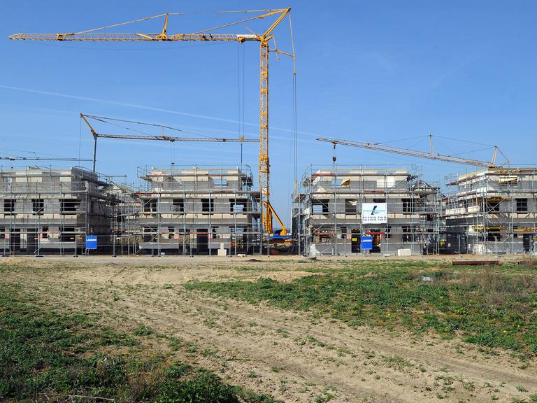 Ein Kran überragt im Neubaugebiet Widdersdorf-Süd in Köln (Nordrhein-Westfalen) im Bau befindliche Häuser. Auf etwa 1200 Baugrundstücken entstehen hier Ein- und Mehrfamilienhäuser.