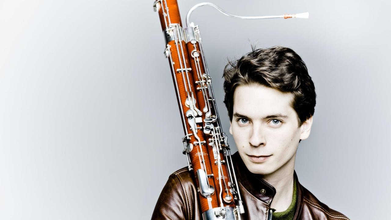 In einer braunen Lederjacke gekleidet, sitzt der Musiker mit seinem Instrument in den Händen In einer braunen Lederjacke gekleidet, sitzt der Musiker mit seinem Instrument in den Händen