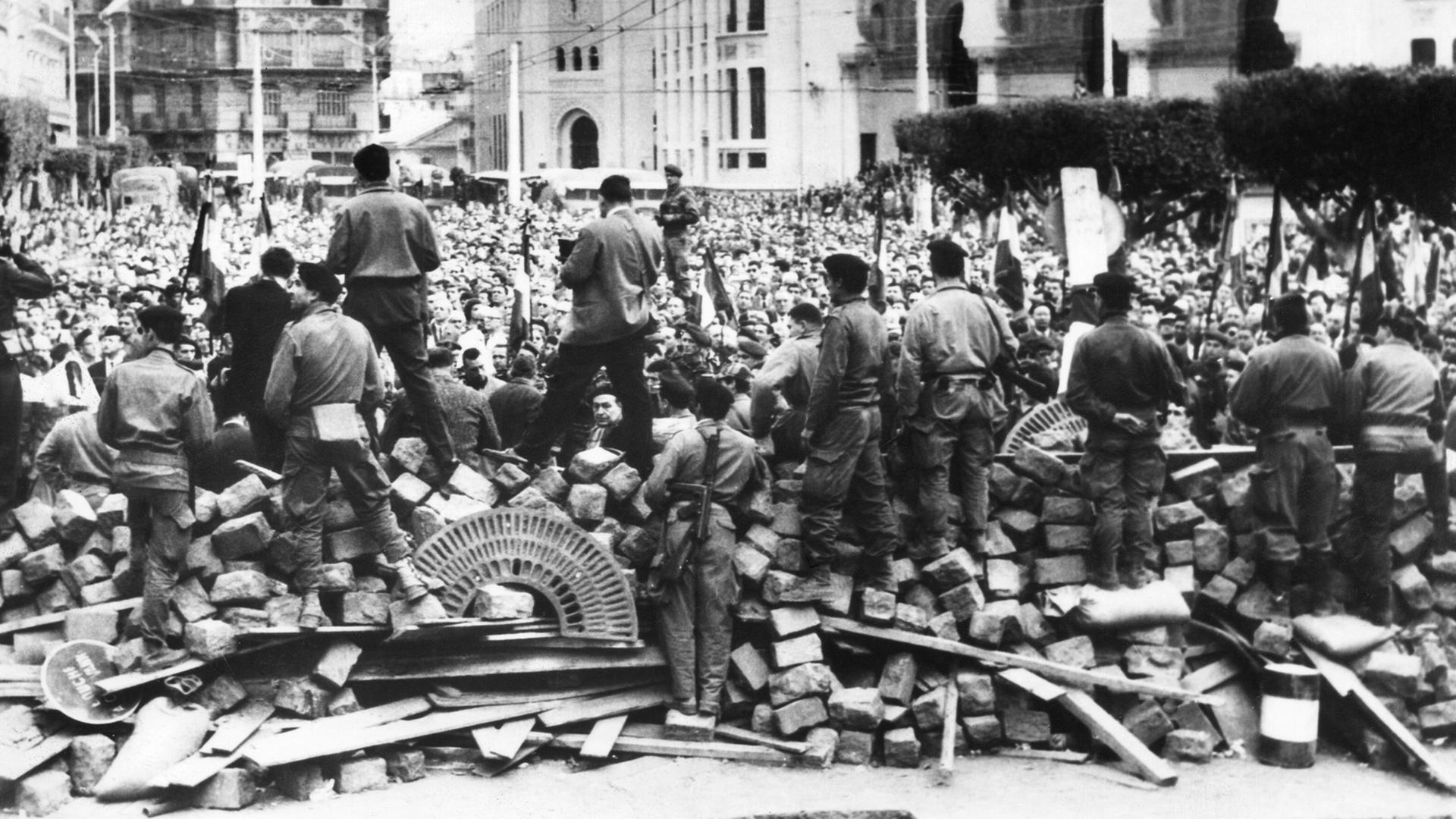 Im Hintergrund Algerien-Franzosen, Gegner der Unabhängigkeit Algeriens, während einer Demonstration Ende Januar 1960 in Algier. Im Vordergrund an den Barrikaden französische Fallschirmspringer. Im Hintergrund Algerien-Franzosen, Gegner der Unabhängigkeit Algeriens, während einer Demonstration Ende Januar 1960 in Algier. Im Vordergrund an den Barrikaden französische Fallschirmspringer.