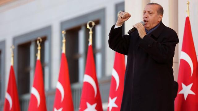 Präsident Erdogan spricht in ein Mikrofon und formt seine rechte Hand zu einer Faust