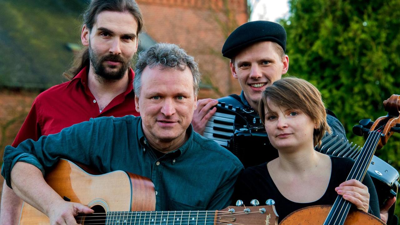 Die vier Musiker der Band Die Grenzgänger sitzen mit ihren Instrumenten zusammen Die vier Musiker der Band Die Grenzgänger sitzen mit ihren Instrumenten zusammen