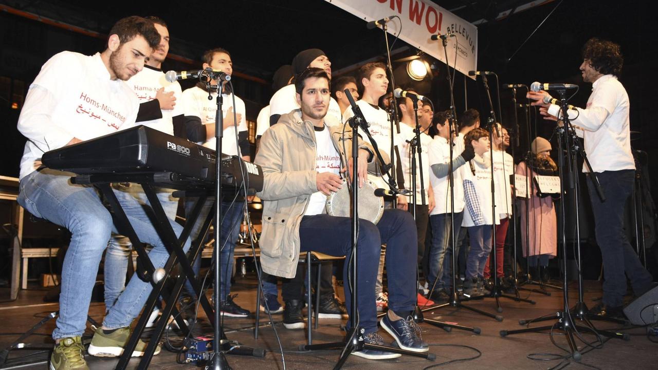 Junge Männer singen und spielen Instrumente auf einer Bühne.