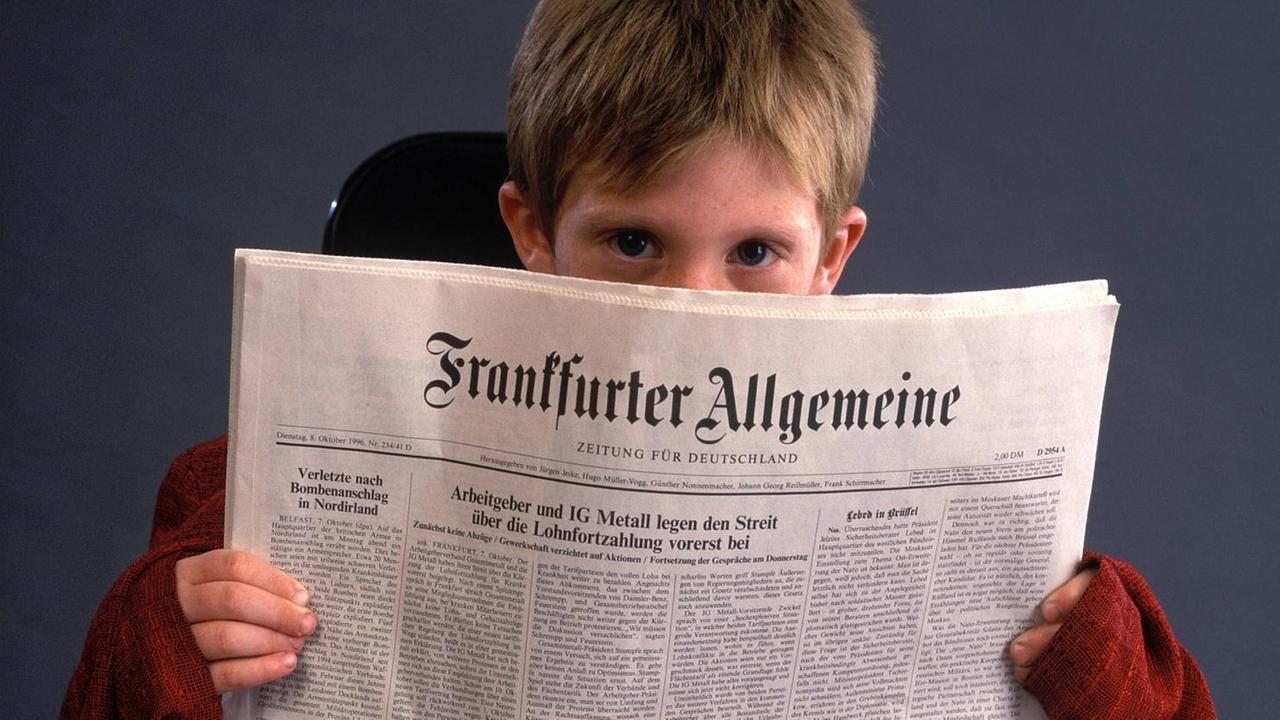 Ein Junge blickt hinter eine Ausgabe der FAZ hervor. Ein Junge blickt hinter eine Ausgabe der FAZ hervor.