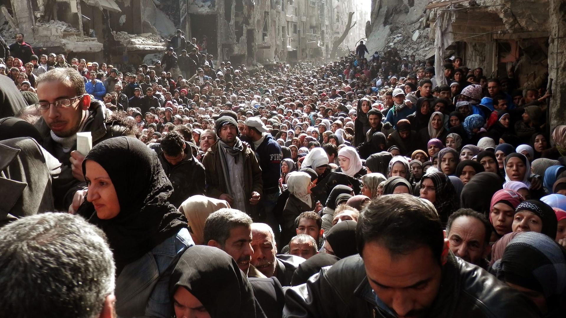 Bewohner des Flüchtlingslagers Jarmuk in Syrien im Februar 2014 während der Essensverteilung. Bewohner des Flüchtlingslagers Jarmuk in Syrien im Februar 2014 während der Essensverteilung.
