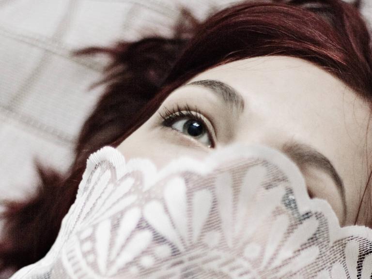 Eine junge Frau liegt mit geöffneten Augen auf dem Boden.