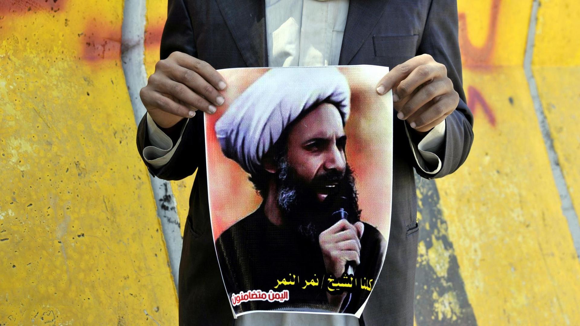 Ein Mann hält im Jemen 2014 ein Foto des schiitischen Geistlichen Nimr al-Nimr in der Hand. Ein Mann hält im Jemen 2014 ein Foto des schiitischen Geistlichen Nimr al-Nimr in der Hand.