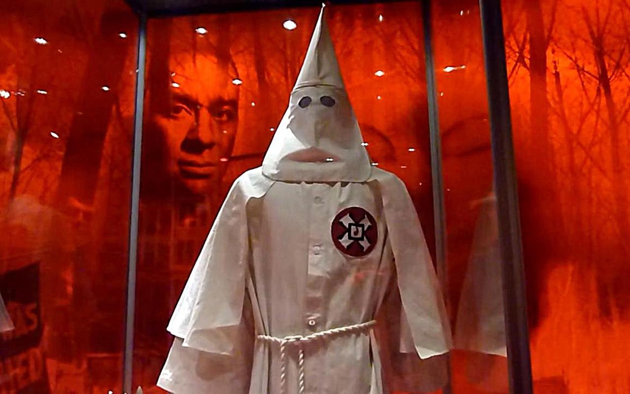 Die Robe eines Ku-Klux-Klan-Mitglieds, dahinter das Gesicht eines Schwarzen in einer Ausstellung in Washington Die Robe eines Ku-Klux-Klan-Mitglieds, dahinter das Gesicht eines Schwarzen in einer Ausstellung in Washington