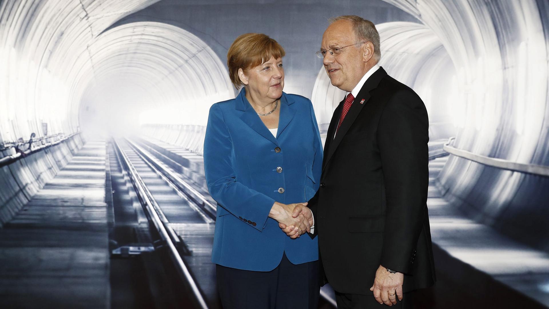 Der Schweizer Bundespräsident Johann Schneider-Ammann steht mit der deutschen Bundeskanzlerin Angela Merkel (l) bei der Eröffnung des Gotthardtunnels im Tunnel. Der Schweizer Bundespräsident Johann Schneider-Ammann steht mit der deutschen Bundeskanzlerin Angela Merkel (l) bei der Eröffnung des Gotthardtunnels im Tunnel.