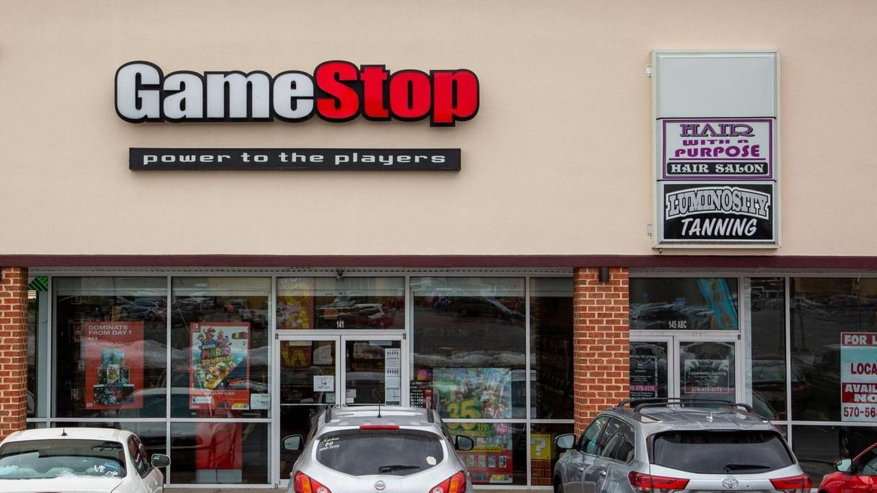 Eine Filiale der Einzelhandeskette Gamestop in den USA. Davor parkende Autos. Eine Filiale der Einzelhandeskette Gamestop in den USA. Davor parkende Autos.