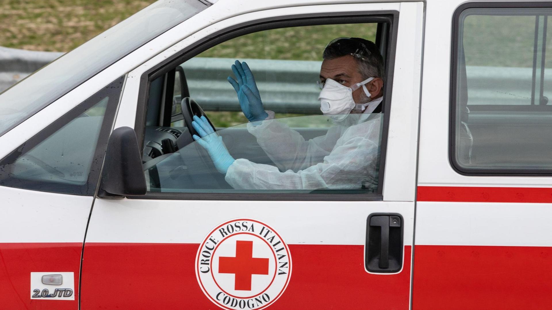 Ein Einatzwagen des italienischen roten Kreuzes mit einem Fahrer mit Maske und Handschuhen in Casalpusterlengo, Mailand in Italien am 23. Februar 2020. Ein Einatzwagen des italienischen roten Kreuzes mit einem Fahrer mit Maske und Handschuhen in Casalpusterlengo, Mailand in Italien am 23. Februar 2020.