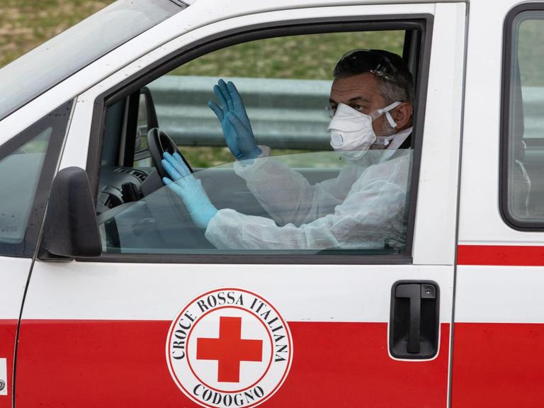 Ein Einatzwagen des italienischen roten Kreuzes mit einem Fahrer mit Maske und Handschuhen in Casalpusterlengo, Mailand in Italien am 23. Februar 2020.