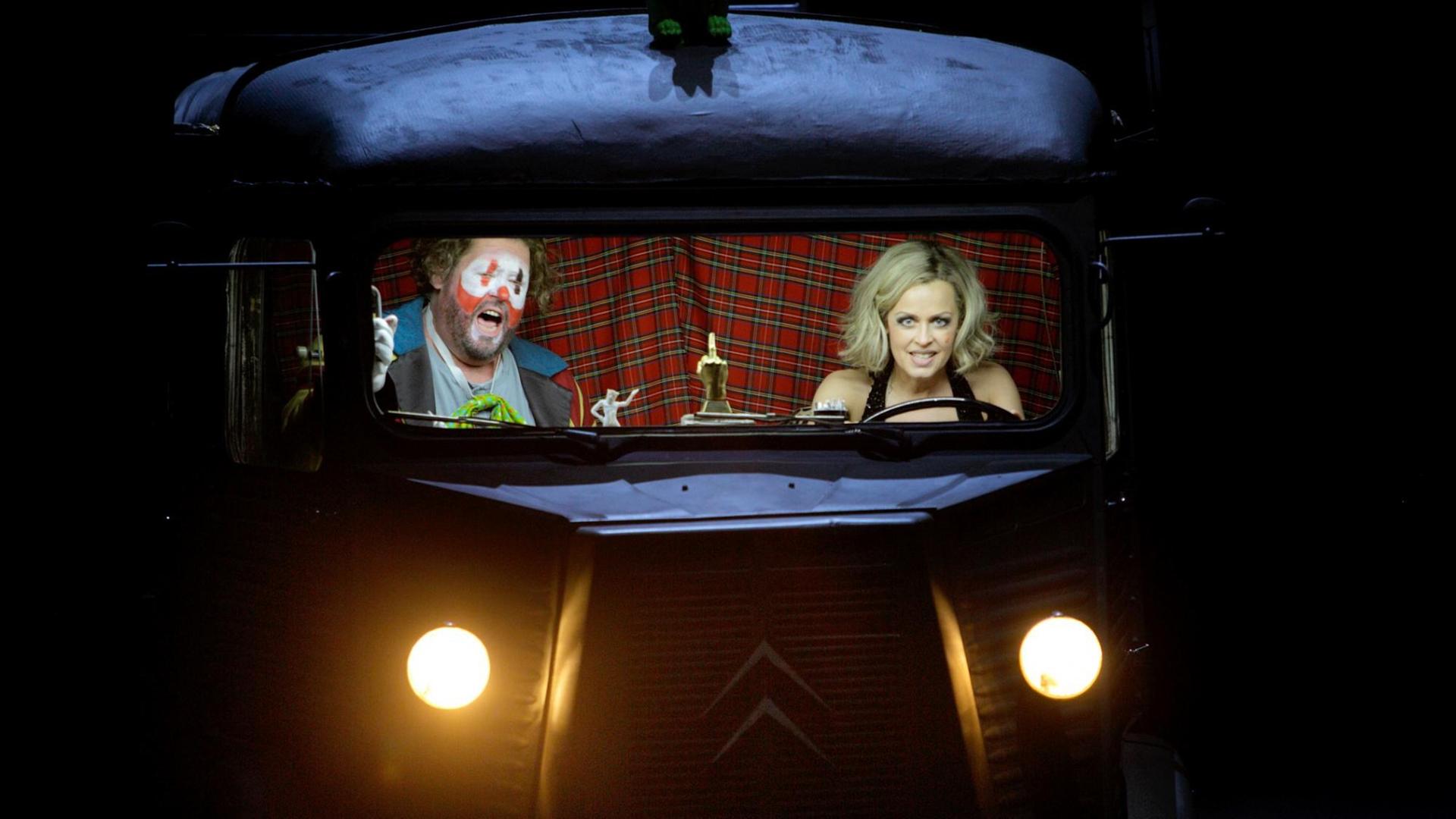 Eine Frau und ein Clown sitzen in einem Bus. Sie steuert das Fahrzeug und er singt, Eine Frau und ein Clown sitzen in einem Bus. Sie steuert das Fahrzeug und er singt,