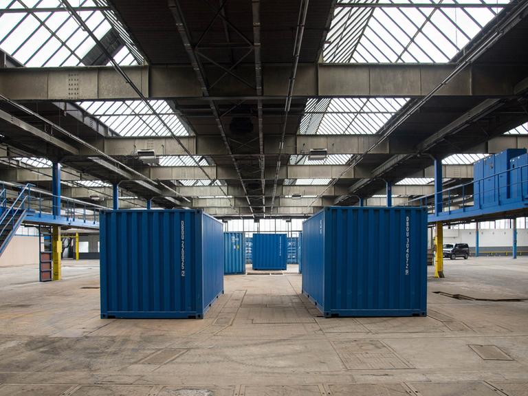 Blaue Container stehen in einer großen Hallte