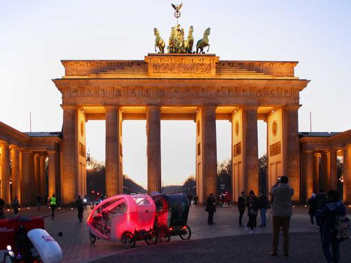 Touristen stehen am 15.02.2017 in Berlin abends am Brandenburger Tor und fotografieren.