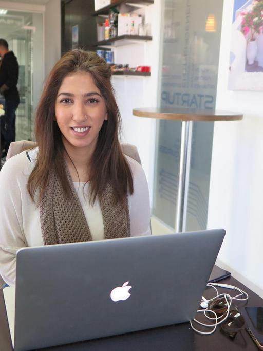 Die junge Start-up-Unternehmerin Laila Akel sitzt vor ihrem Laptop in einem Café.