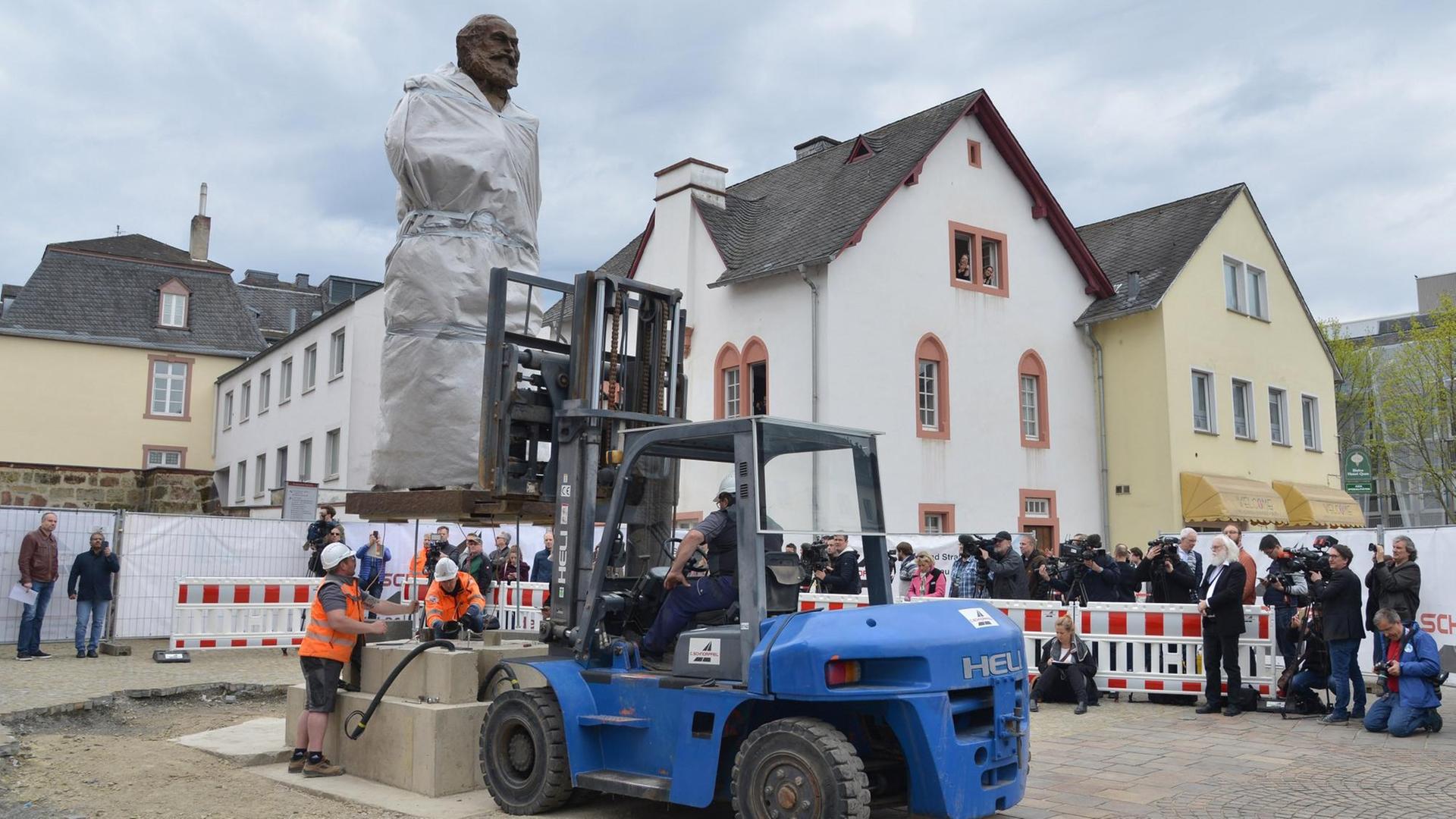 Die größtenteils mit einer Plane verdeckte 2,3 Tonnen schwere und 4,40 Meter große Karl-Marx-Statue des chinesischen Künstlers Wu Weishan wird in Trier aufgestellt. Die größtenteils mit einer Plane verdeckte 2,3 Tonnen schwere und 4,40 Meter große Karl-Marx-Statue des chinesischen Künstlers Wu Weishan wird in Trier aufgestellt.