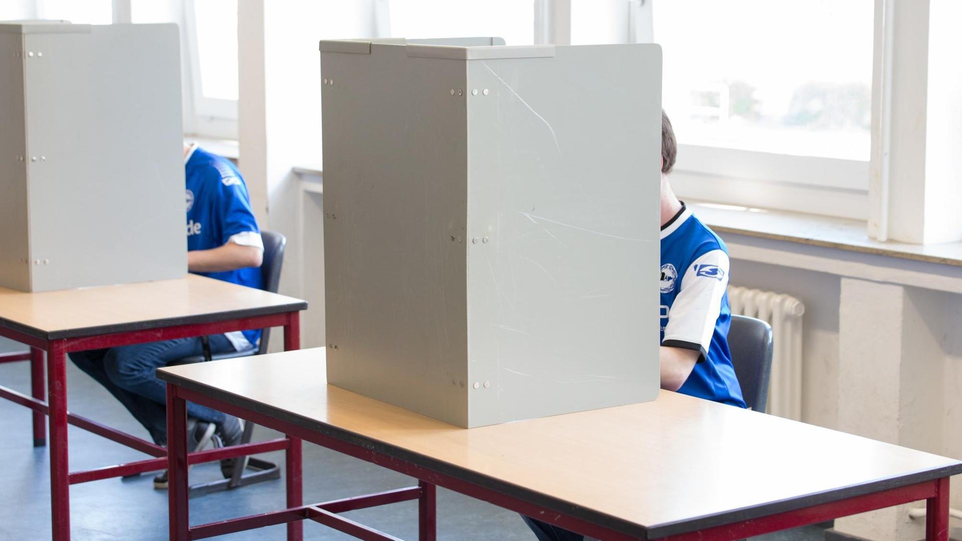 Zwei Wähler gekleidet in ein Fußballtrikot sitzen in einem Wahllokal in einer Wahlkabine Zwei Wähler gekleidet in ein Fußballtrikot sitzen in einem Wahllokal in einer Wahlkabine