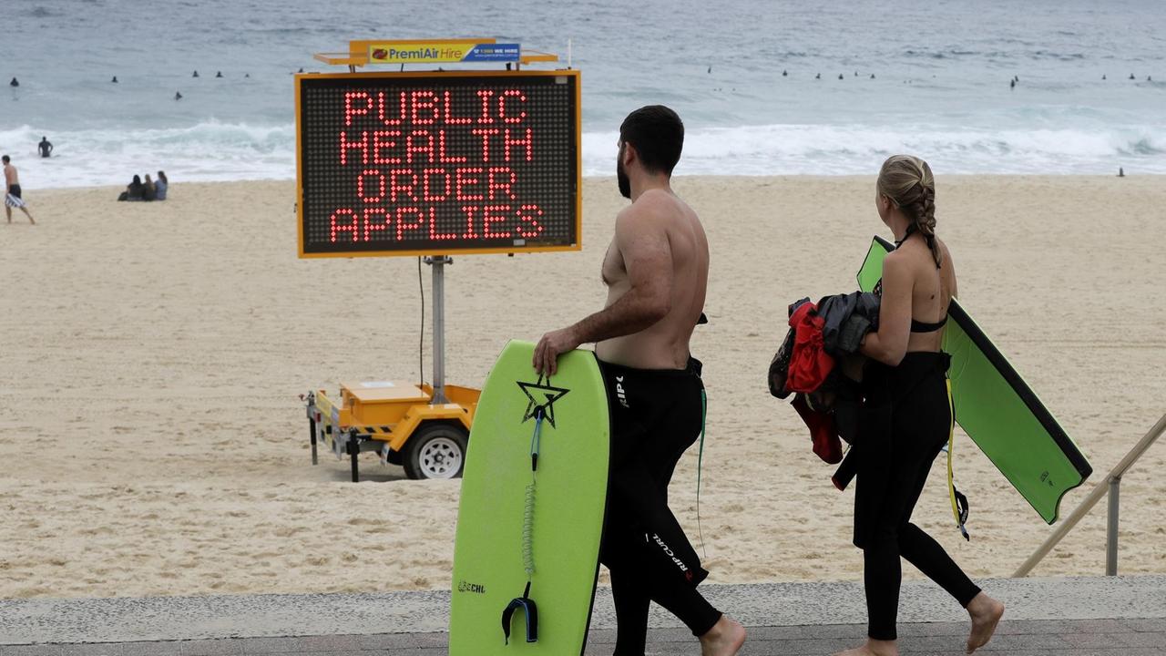Ein Schild warnt Menschen an einem Strand in Sydney mit "Public health order applies". Ein Schild warnt Menschen an einem Strand in Sydney mit "Public health order applies".