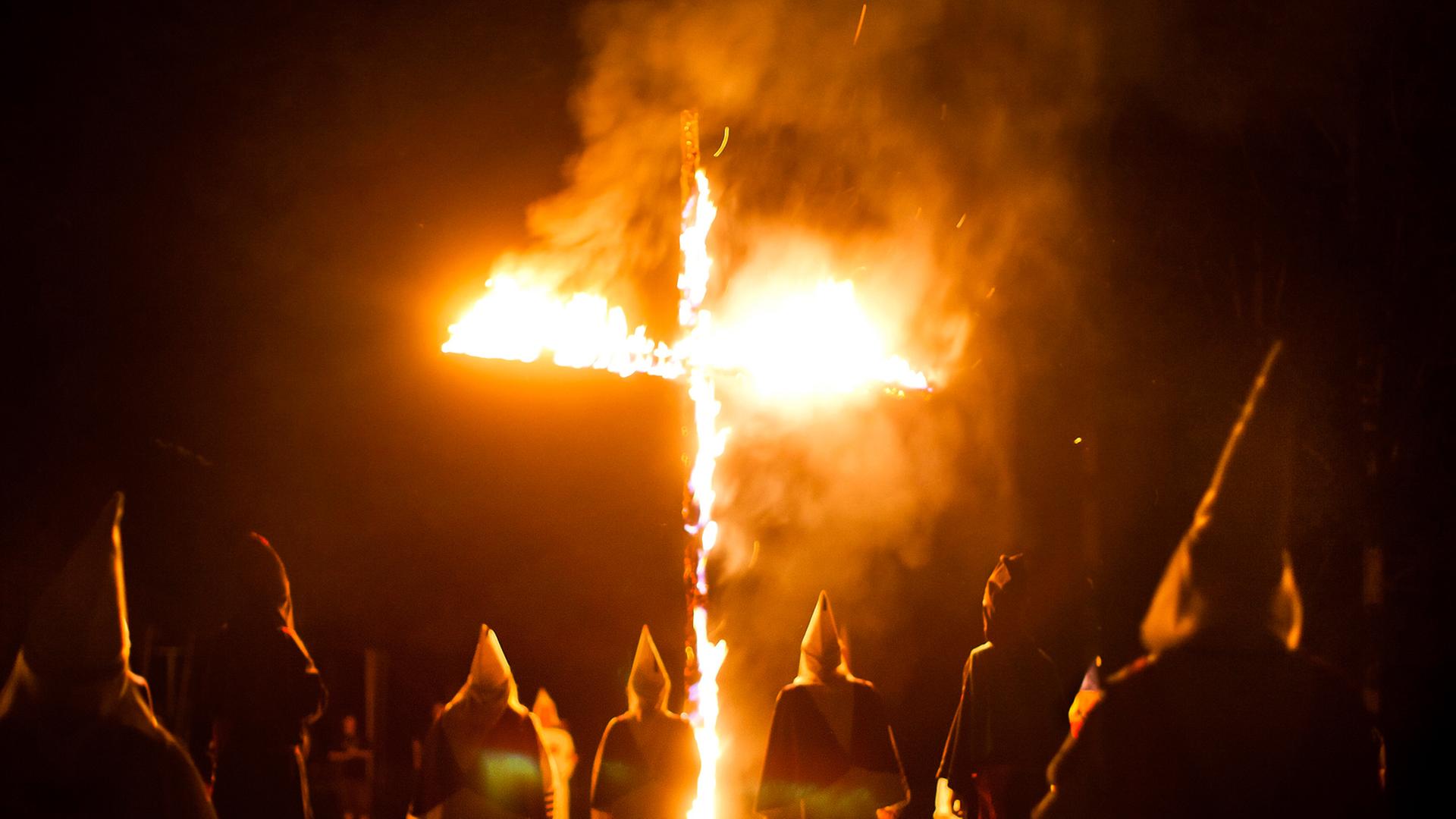 Mitglieder des Geheimbundes Ku-Klux-Klan in den USA stehen in weißen Gewändern und Kapuzen um ein brennendes Kreuz. Mitglieder des Geheimbundes Ku-Klux-Klan in den USA stehen in weißen Gewändern und Kapuzen um ein brennendes Kreuz.