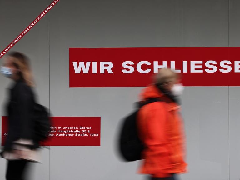 Passanten gehen in der Innenstadt an einem geschlossen Ladenlokal vorbei. Die Inzidenz bei den Corona-Neuinfektionen in Nordrhein-Westfalen bewegt sich um die Marke von 100.