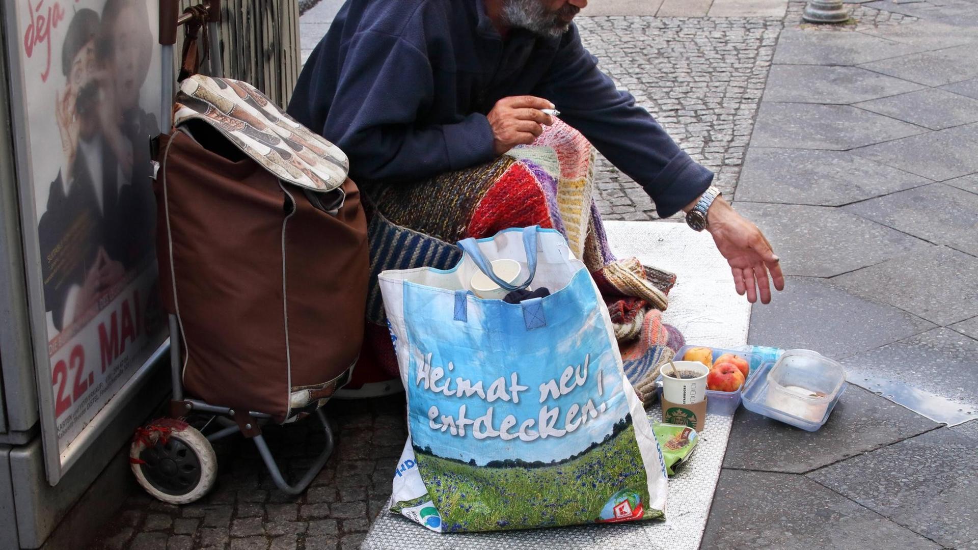 Ein bettelnder Mann bittet Passanten in Berlin-Mitte um Spenden. Obdachlosigkeit und Armut in der Hauptstadt. Immer mehr Menschen leben in Berlin ohne festen Wohnsitz auf der Straße.