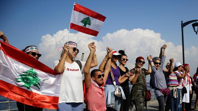Libanesen halten libanesische Flaggen während sie eine Menschenkette als Zeichen nationaler Einheit bilden.