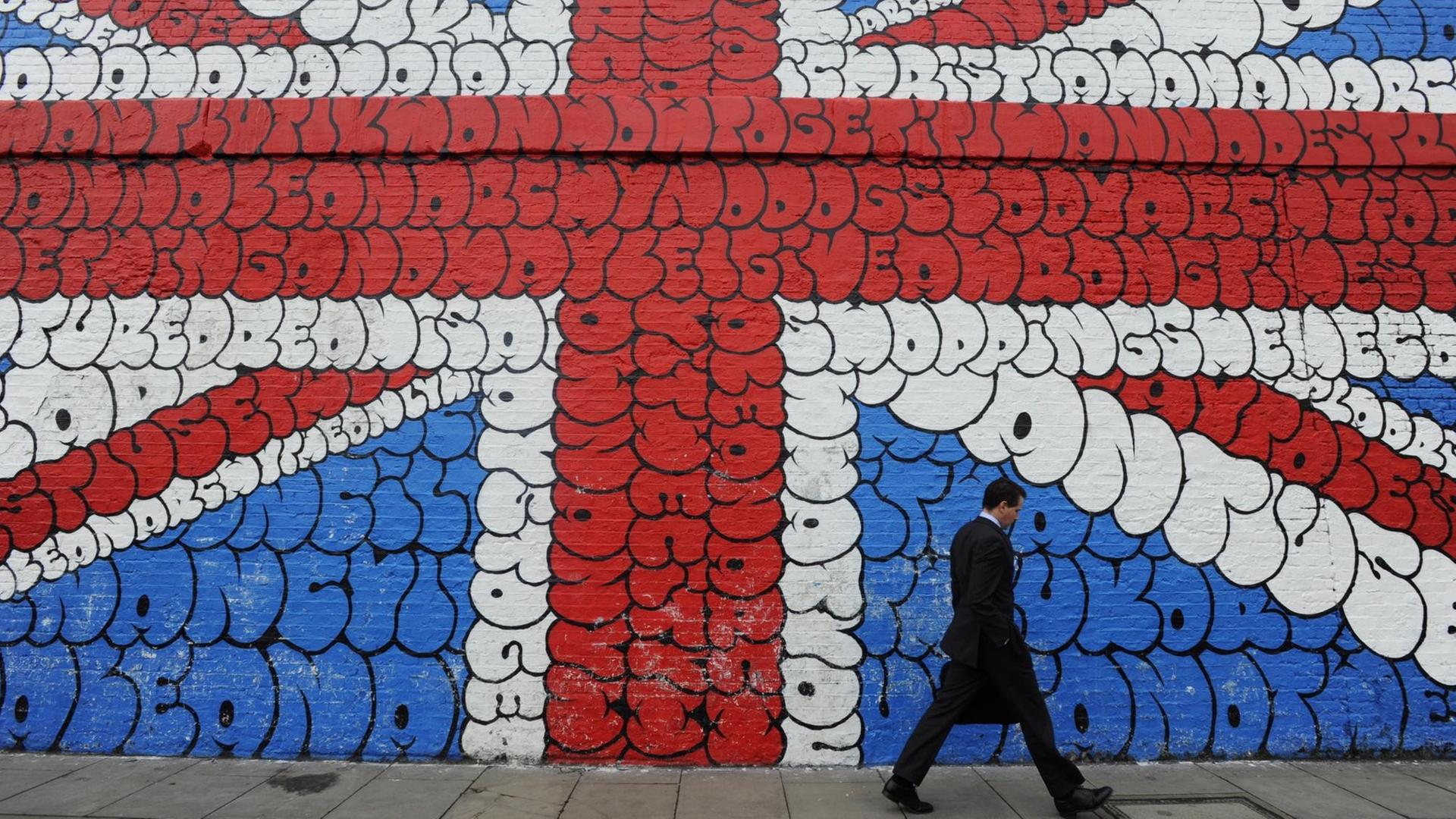 Ein Mann läuft an einem Grafitti, das die britische Flagge zeigt, vorbei. Ein Mann läuft an einem Grafitti, das die britische Flagge zeigt, vorbei.