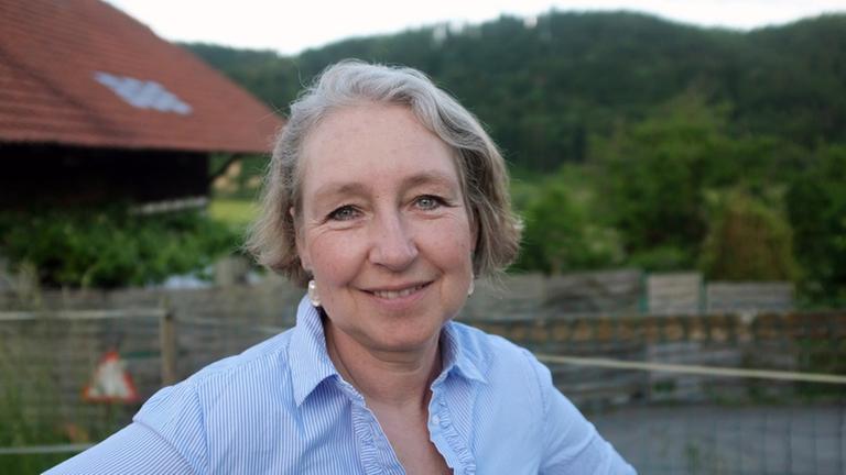 Porträt von Martina King mit dem Blick auf eine grüne Landschaft. Porträt von Martina King mit dem Blick auf eine grüne Landschaft.