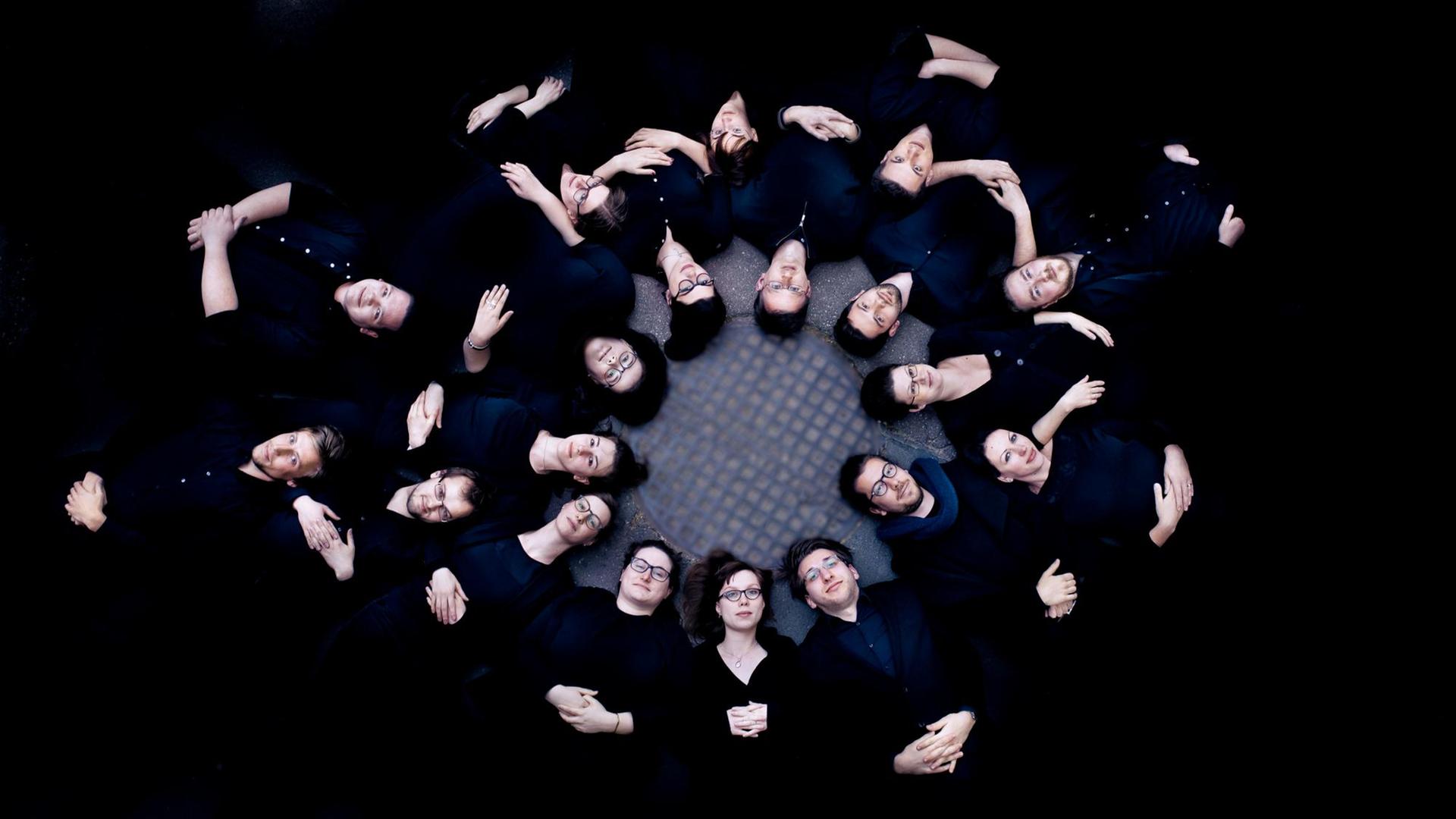Gruppenbild der Sänger liegend vor schwarzem Hintergrund Gruppenbild der Sänger liegend vor schwarzem Hintergrund