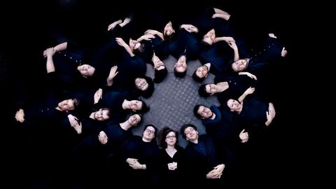 Gruppenbild der Sänger liegend vor schwarzem Hintergrund