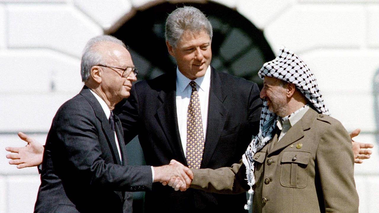 Jitzchak Rabin (li.) und Jassir Arafat (re.) reichen sich in Washington die Hand anlässlich der Unterzeichnung des Gaza-Jericho-Abkommens, in der Mitte US-Präsident Bill Clinton