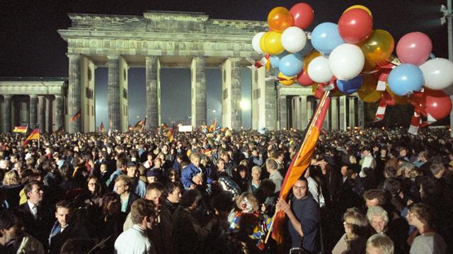 Ausgelassen feiert eine riesige Menschenmenge in der Nacht vom 2. auf den 3. Oktober 1990 vor dem Brandenburger Tor in Berlin die deutsche Wiedervereinigung.