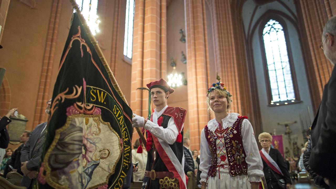 Menschen mit Fahnen und traditionellen Kostümen beim Festgottesdienst im Frankfurter Kaiserdom
