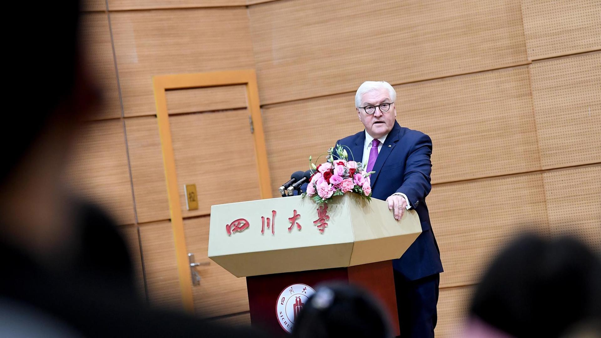Frank-Walter Steinmeier hält sich an einem Rednerpult fest, auf dem chinesische Schriftzeichen stehen. Frank-Walter Steinmeier hält sich an einem Rednerpult fest, auf dem chinesische Schriftzeichen stehen.