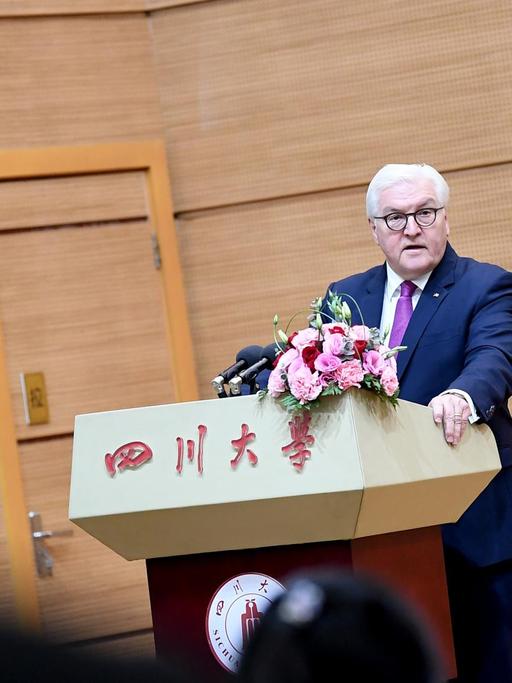 Frank-Walter Steinmeier hält sich an einem Rednerpult fest, auf dem chinesische Schriftzeichen stehen.