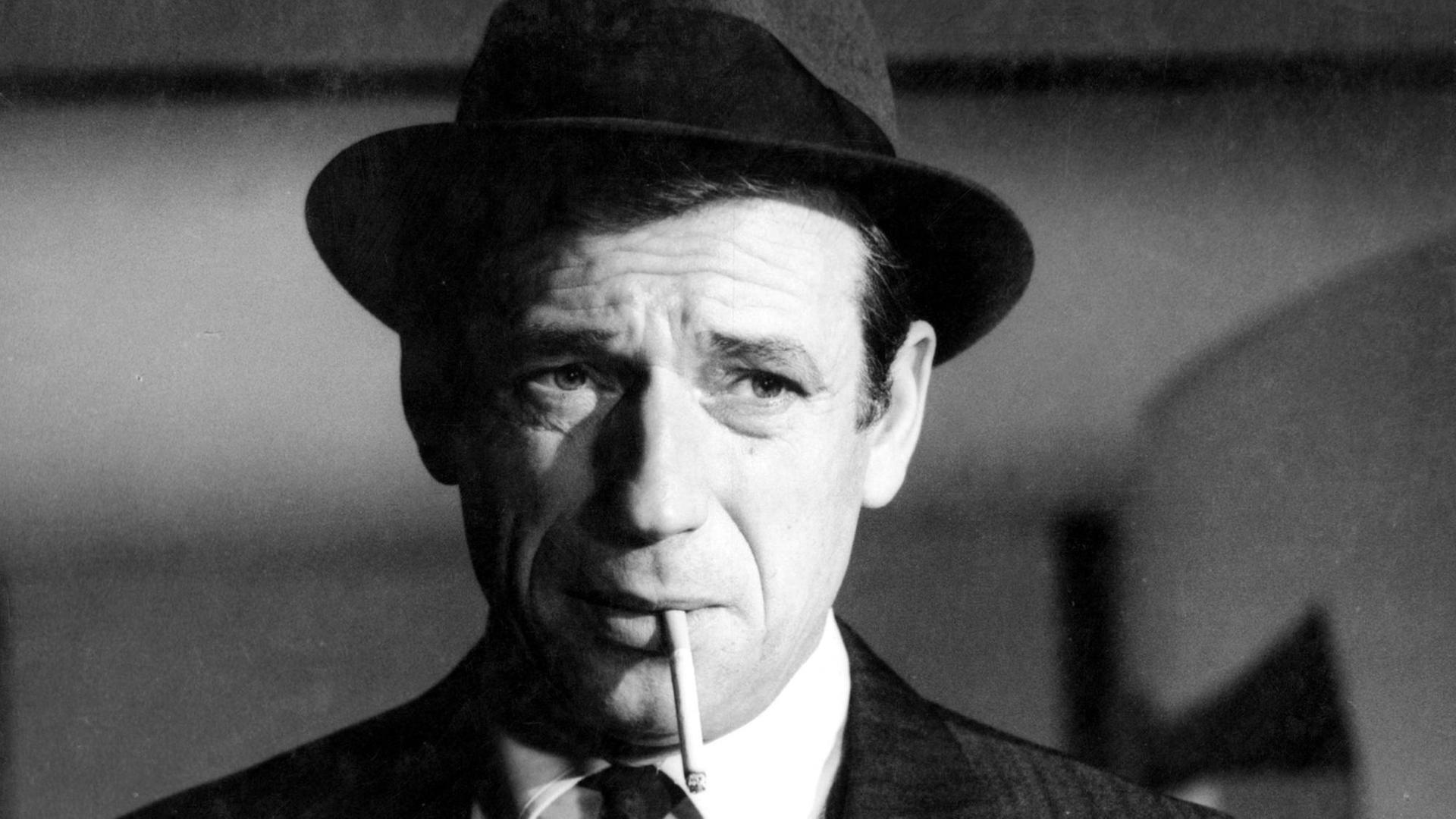 Eine Szene aus dem Film "Compartiment tueurs" von dem Regisseur Costa-Gavras. Sie zeigt Yves Montand mit Hut und Zigarette im Mund. Eine Szene aus dem Film "Compartiment tueurs" von dem Regisseur Costa-Gavras. Sie zeigt Yves Montand mit Hut und Zigarette im Mund.