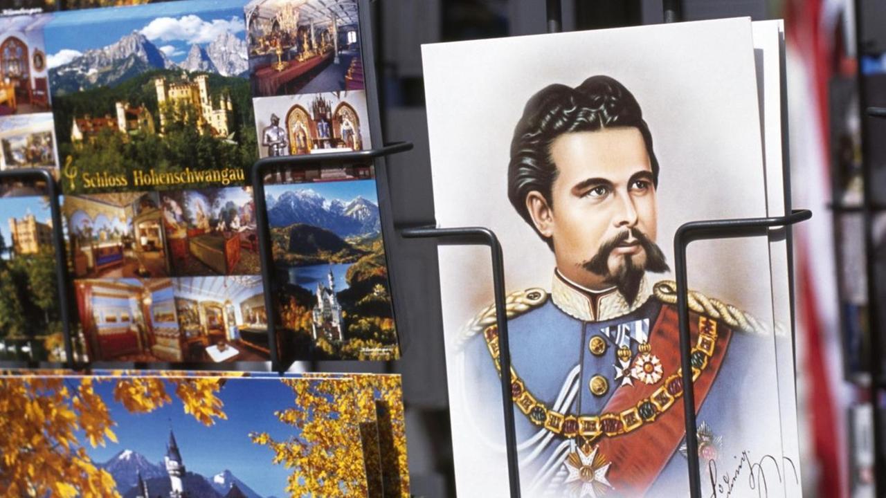 Ansichtskarte von Ludwig II. in einem Kartenständer mit anderen Postkarten
