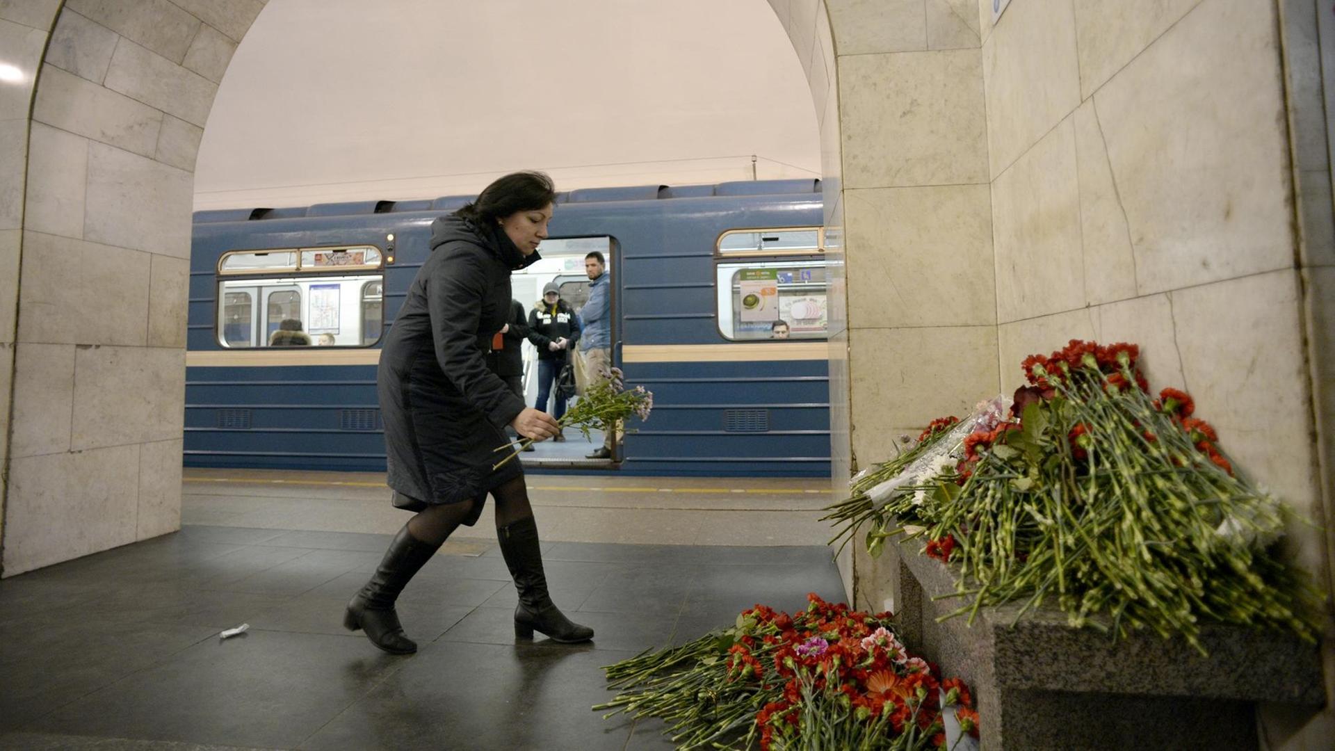 Eine Frau liegt an der U-Bahnstation Technologisches Institut in St. Petersburg Blumen nieder.
