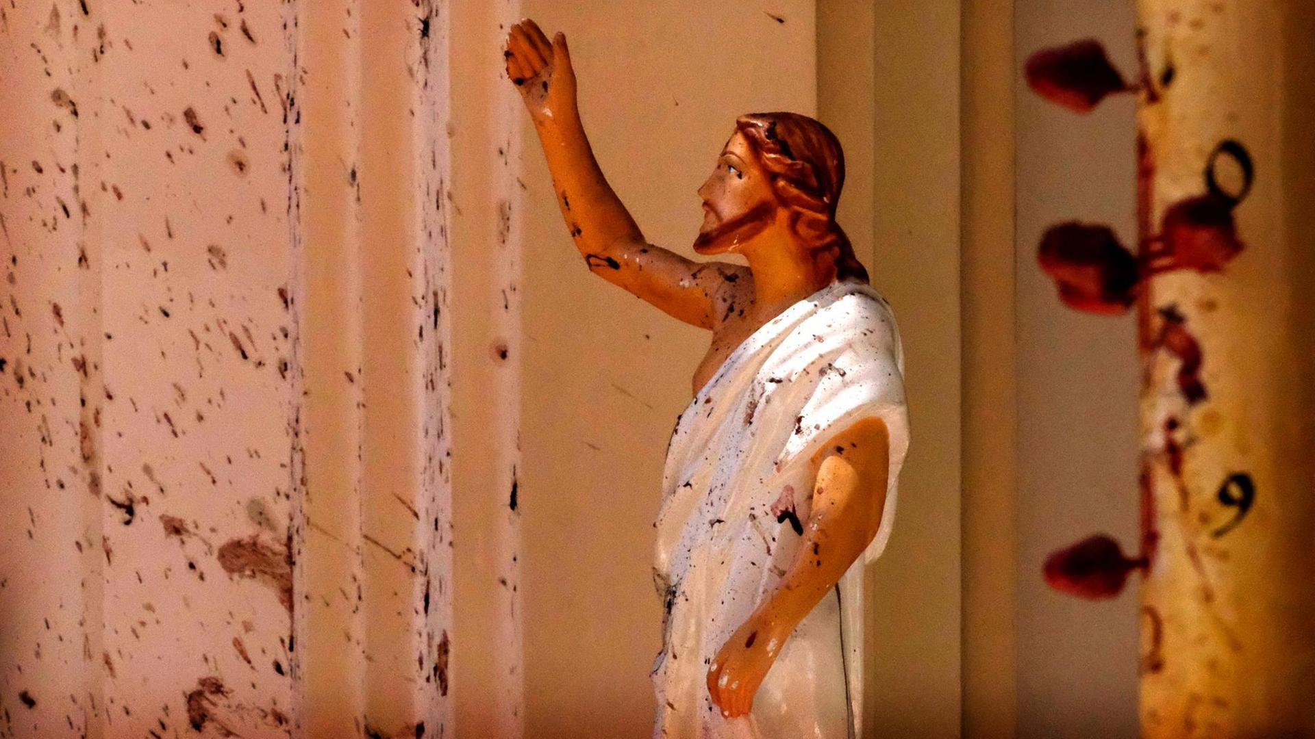 Blutflecken sind an der Wand und auf einer Jesus Christus-Figur in der durch eine Explosion beschädigte St.-Sebastians-Kirche. Blutflecken sind an der Wand und auf einer Jesus Christus-Figur in der durch eine Explosion beschädigte St.-Sebastians-Kirche.