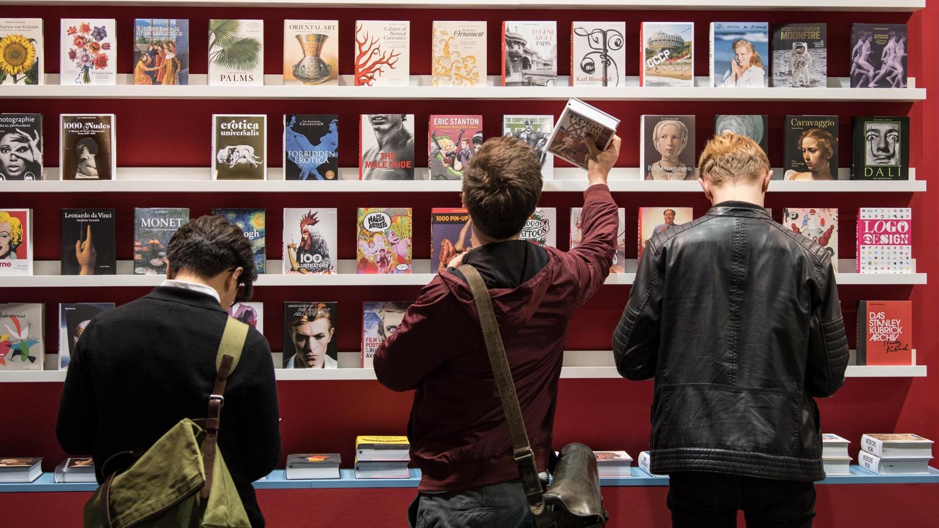 Besucher stehen auf der Buchmesse in Frankfurt am Main (Hessen) vor einem Bücherregal. Besucher stehen auf der Buchmesse in Frankfurt am Main (Hessen) vor einem Bücherregal.