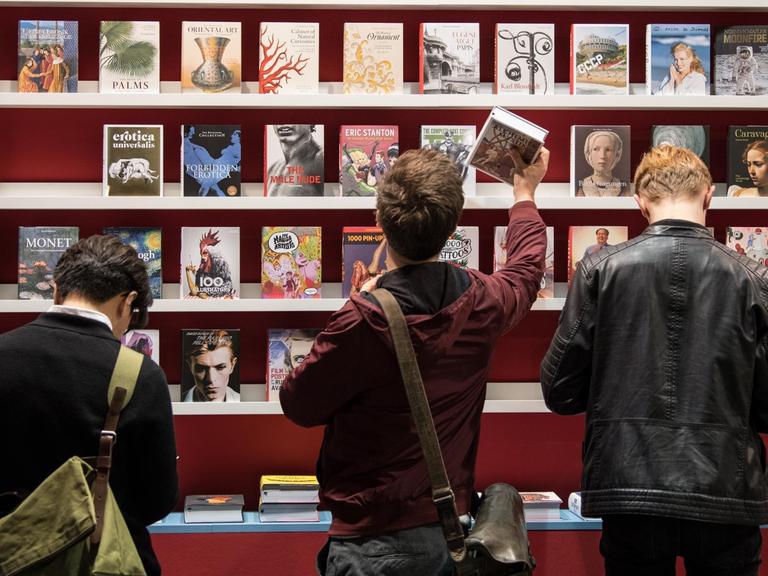 Besucher stehen auf der Buchmesse in Frankfurt am Main (Hessen) vor einem Bücherregal.
