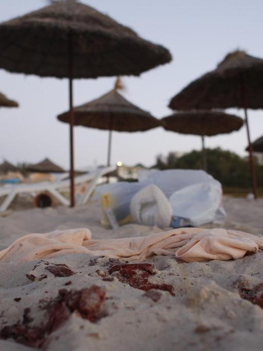 Am Strand von Sousse sind Blutspuren und eine umgestürzte Liege vor Sonnenschirmen zu sehen.