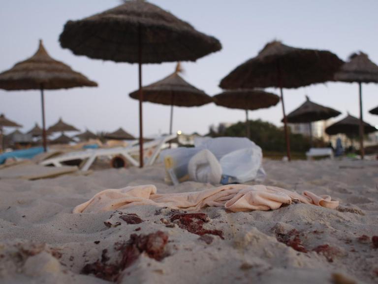 Am Strand von Sousse sind Blutspuren und eine umgestürzte Liege vor Sonnenschirmen zu sehen.