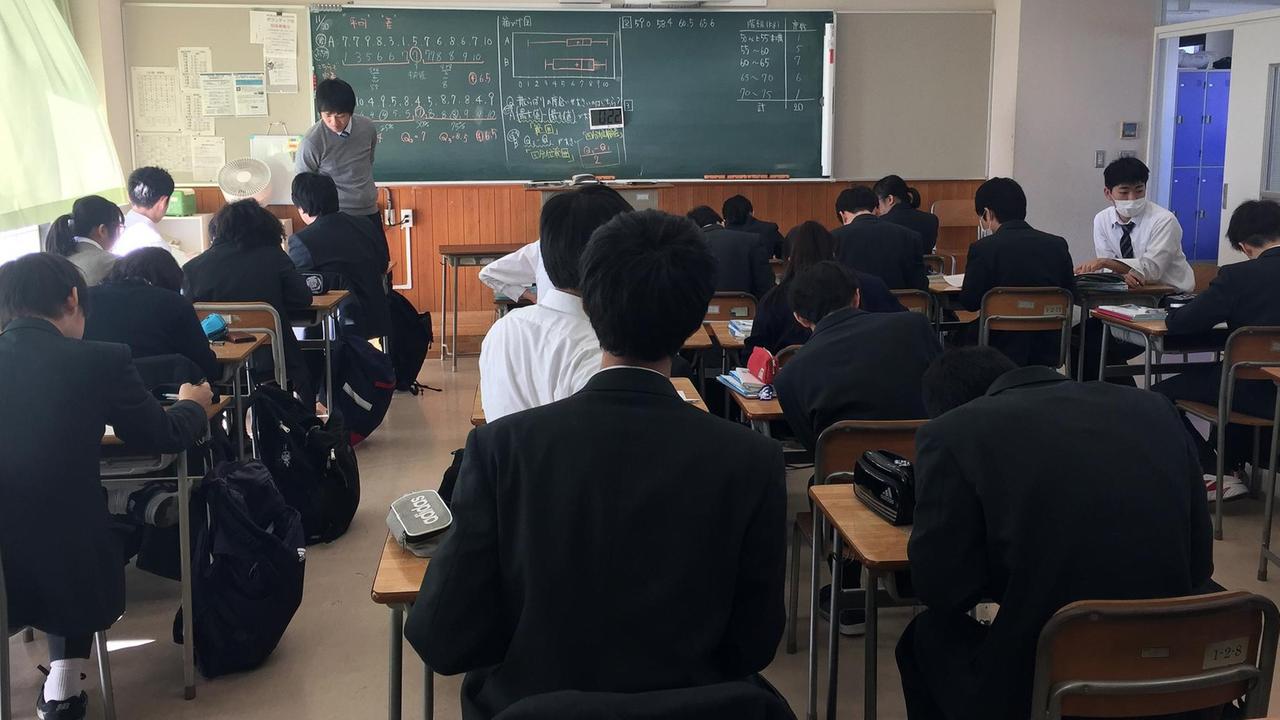 Matheunterricht in der Tama Oberschule. In einem Klassenraum sitzen Jungen und Mädchen gekleidet in Schuluniform – weiße Blusen, schwarze Jacken. Matheunterricht in der Tama Oberschule. In einem Klassenraum sitzen Jungen und Mädchen gekleidet in Schuluniform – weiße Blusen, schwarze Jacken.