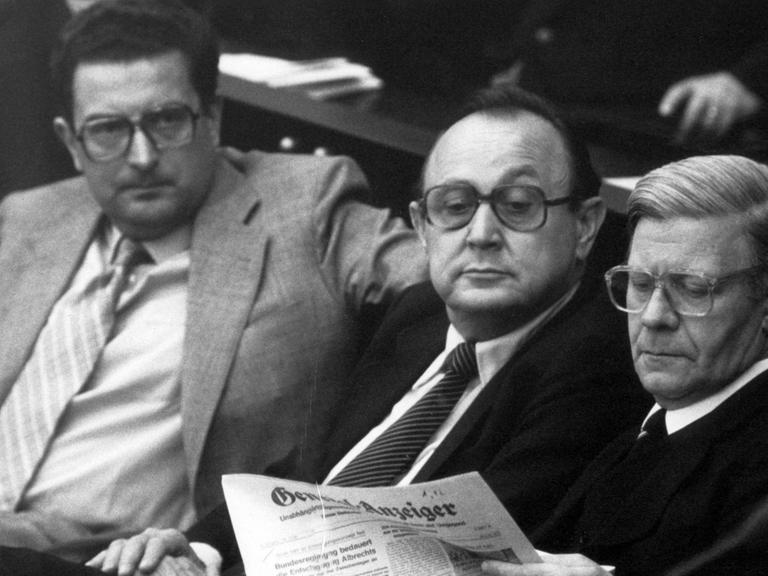 Bundeskanzler Helmut Schmidt (SPD, r) sitzt 1980 auf der Regierungsbank im Bonner Bundestag und liest den General-Anzeiger. Bundesaußenminister Hans Dietrich Genscher (FDP, M) liest mit. Links Innenminister Gerhart Baum (FDP).
