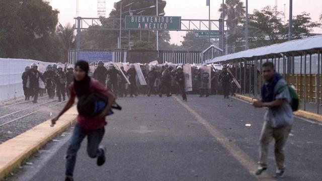 Migranten aus Mittelamerika laufen während Zusammenstößen mit der Polizei nahe der Grenze zwischen Guatemala und Mexiko vor mexikanischen Beamten weg.